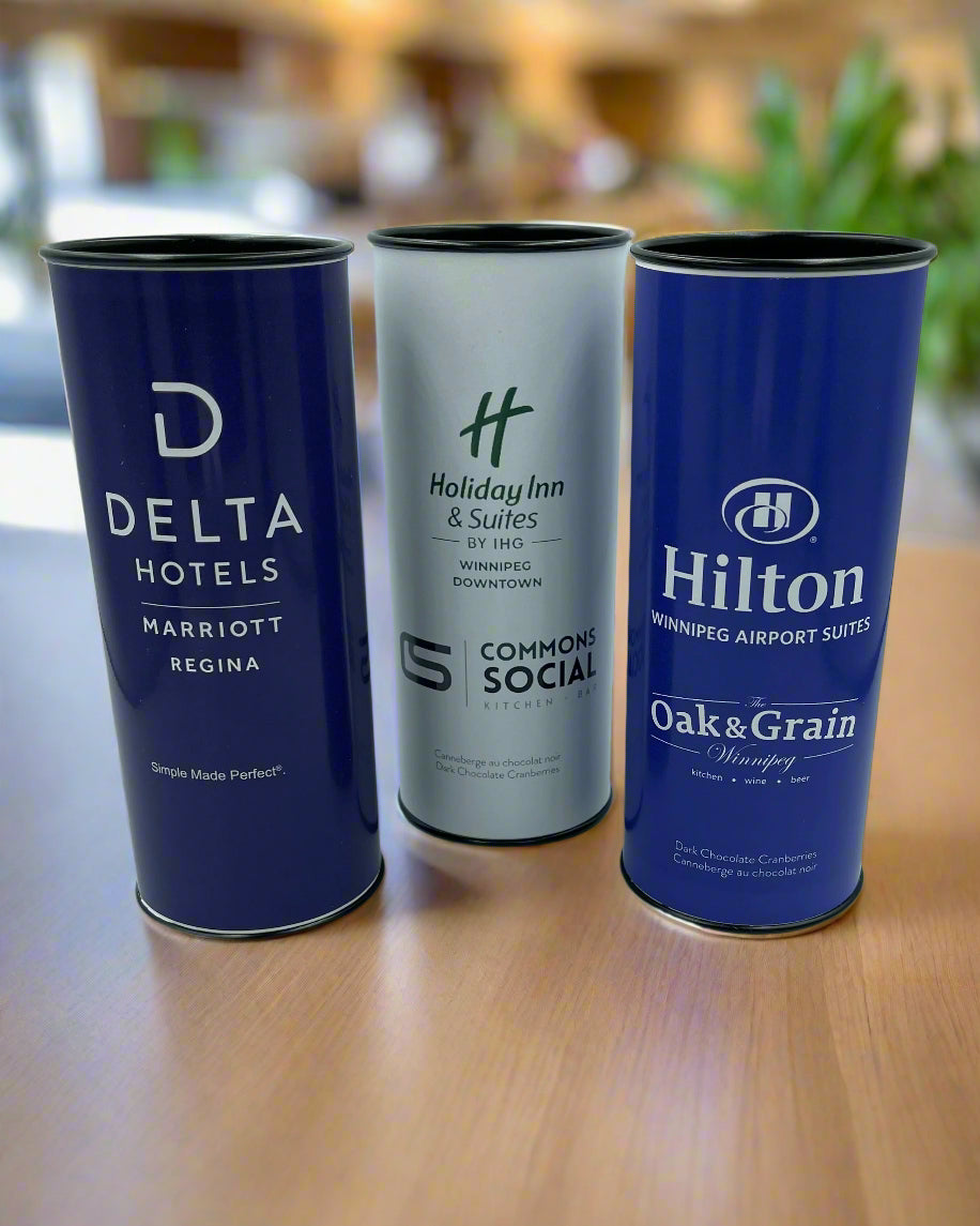 Three cylindrical containers with branding for Delta Hotels, Holiday Inn & Suites, and Hilton.