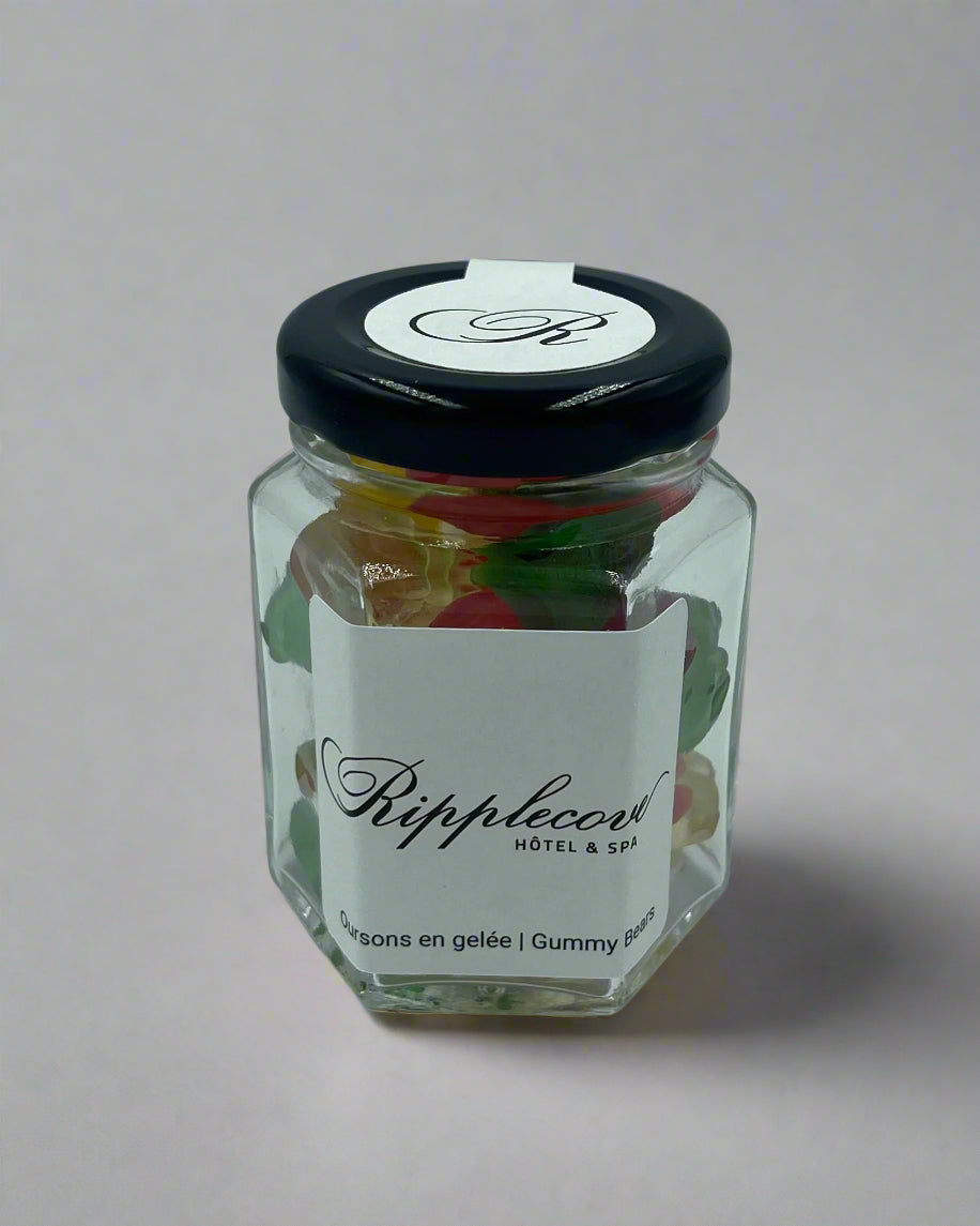 Hexagonal jar of gummy bears with a white label and black lid on a light gray background